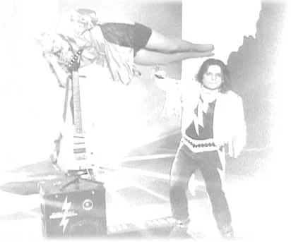 Faded promotional photo: a woman levitating over an electric guitar while Chezaday gestures beside a lightning-bolt amplifier